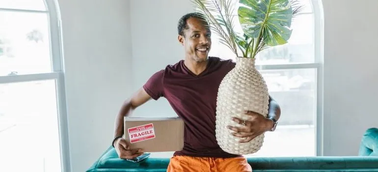 A man holding a cardboard box and a vase.