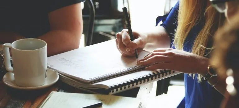 A woman writing down a moving checklist in her attempt to prevent moving day injuries.