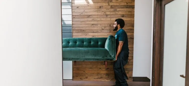 a man carrying a green couch