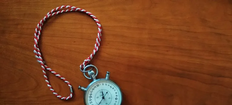A metal timer is lying on a wooden floor.