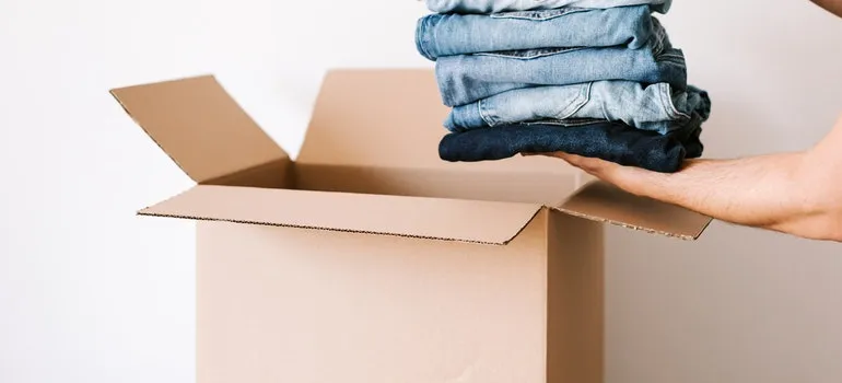 A person is putting clothes into a box.