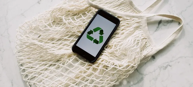 a phone with a recycling symbol on it is lying on a bag.