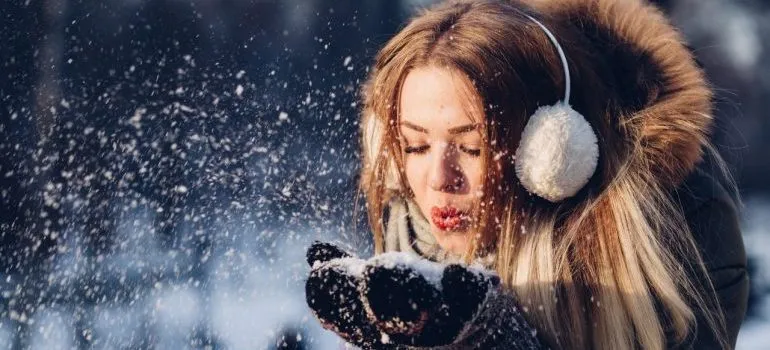 Woman blowing snow from hands