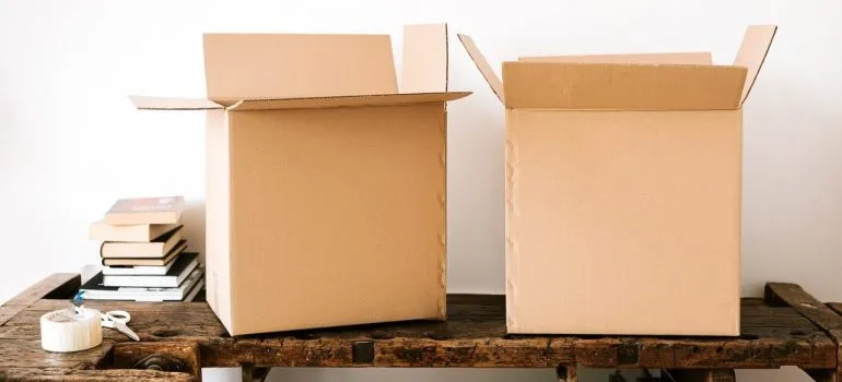a small set of books standing near packing tape, scissors and cardboard boxes