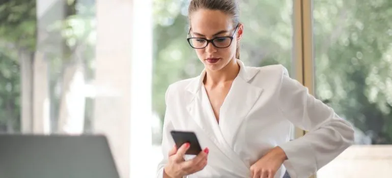 a woman using her phone after she was able to find reliable Bethesda movers