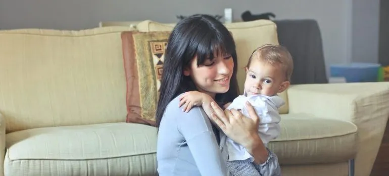 Babysitter holding a child before family prepares for moving long-distance with toddlers