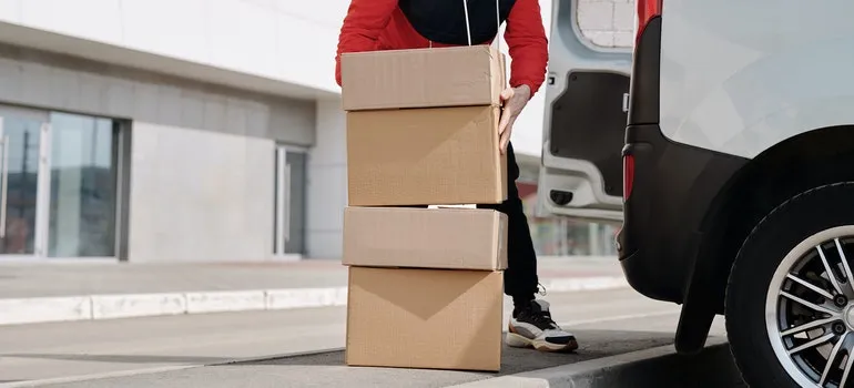 A man is loadin boxes into a truck.