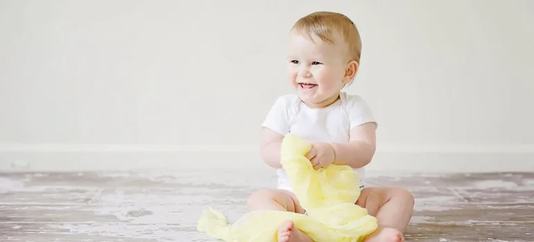 baby holding a blanket and smiling
