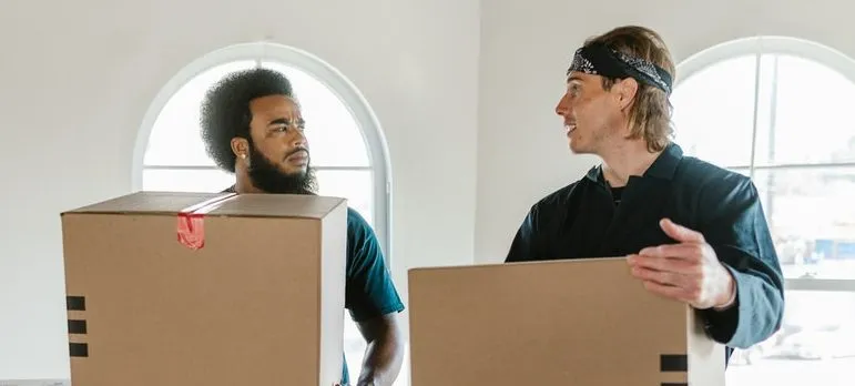 two movers carrying boxes that can help safely move your grill