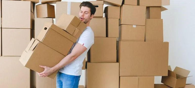 man holding cardboard boxes trying to relocate your Germantown household in a week