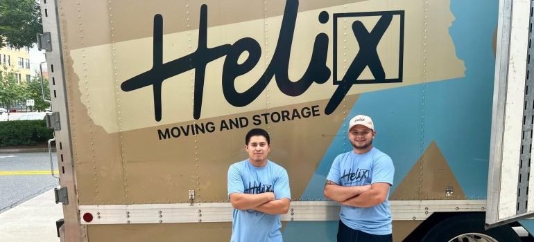 Two movers next to a moving truck.