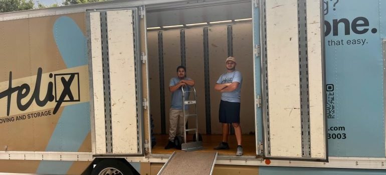 Two professional movers in a moving truck waiting to load items.