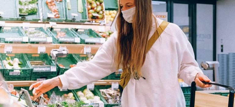 a woman in a white long sleeve shirt picking fruits at the grocery