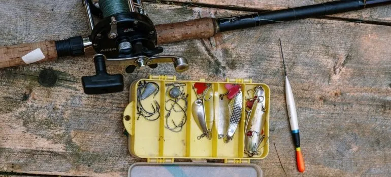 a fishing rod with baits next to it to represent how one should pack fishing equipment for moving