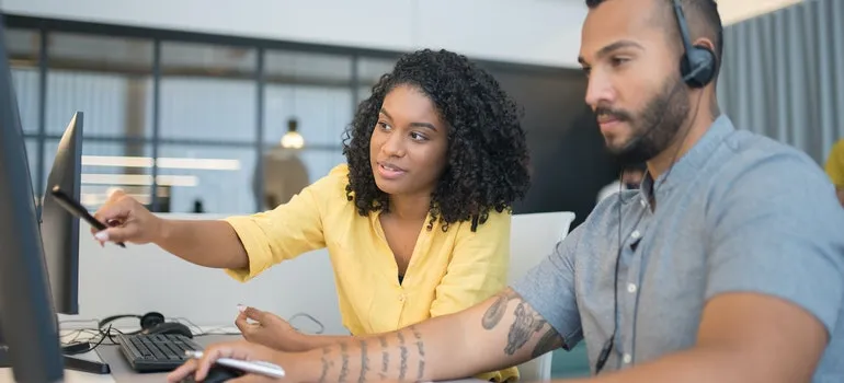 A woman showing a man something on the screen.