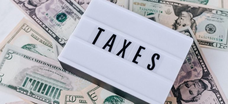 a pile of dollars with a white item saying taxes on it