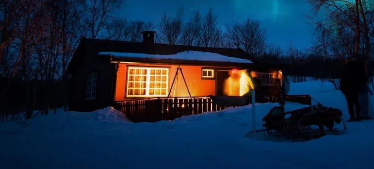 small wooden hut under aurora borealis