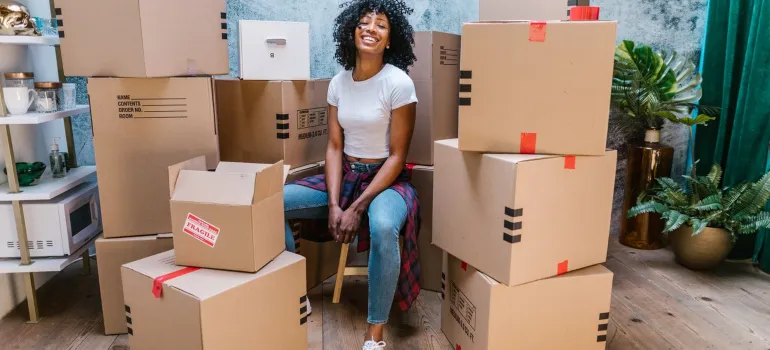 a woman smiling while sitting in the middle of cardboard boxes