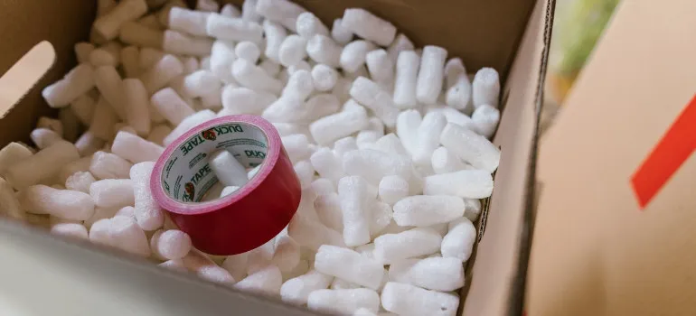 Styrofoam peanuts and tape in a box used to wrap fragile items for long haul moves