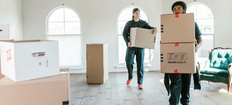 two movers handling boxes inside an empty home