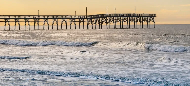An ocean pier at sunset surrounded by small waves