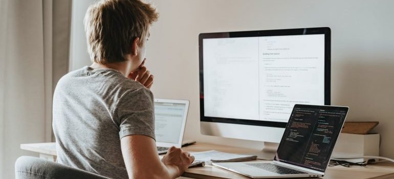 A man sitting in front of the computer and thinking how to start unpacking after moving to Silver Spring