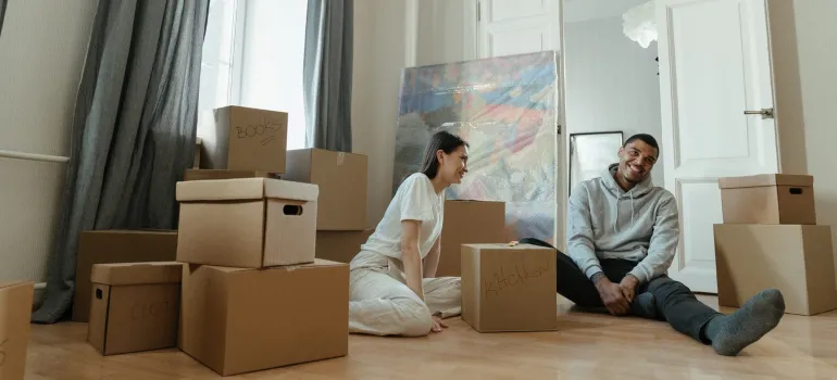 a couple having fun while in the midst of packing in their living room