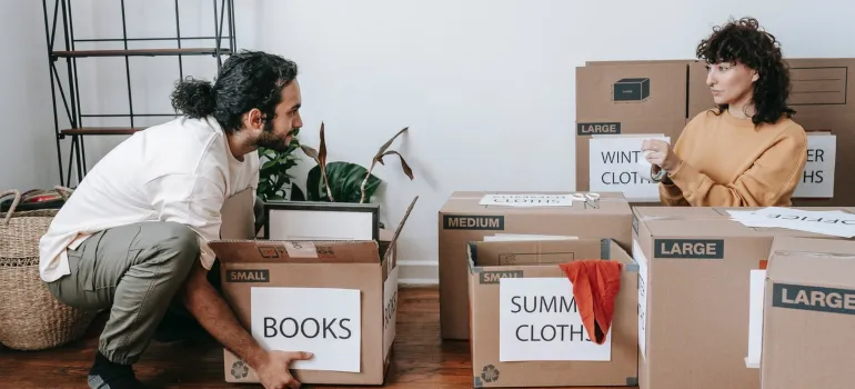 a happy couple packing for a move from one Maryland city to another while handling items in their living room