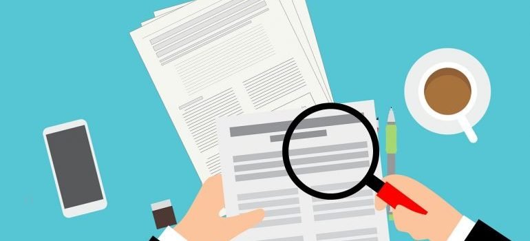 A person holding magnifying glass in front of a piece of paper