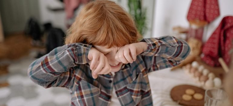 A boy crying while covering his eyes