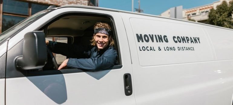 a man riding a white van of a moving company
