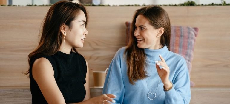 Two girls talking in front of the laptop - research is important to find reliable movers in Virginia