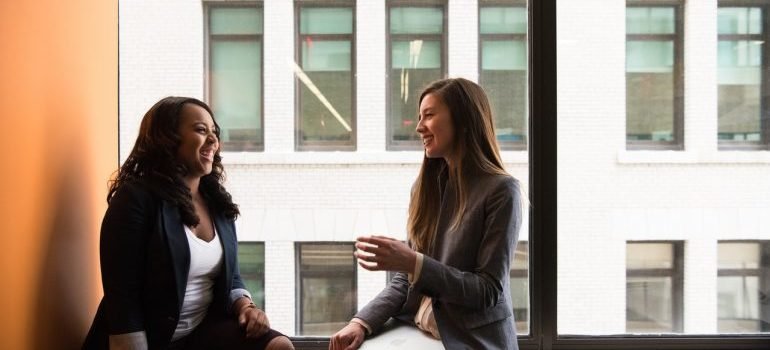 two women sitting near a window talking
