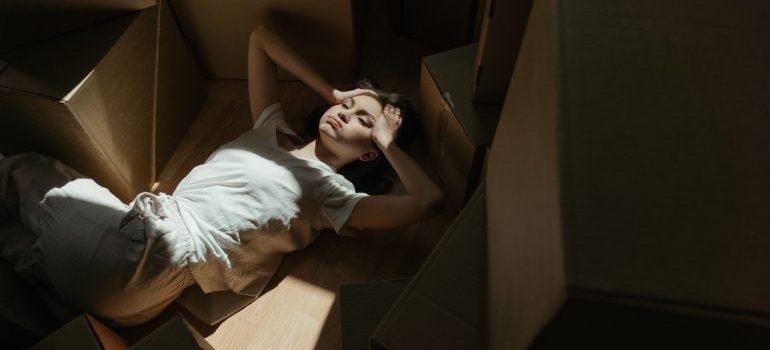 Woman lying on the floor surrounded by moving boxes