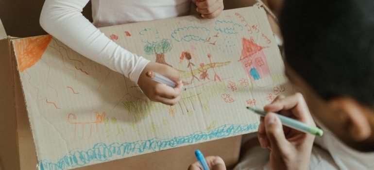 Kids drawing on moving box - this is a great activity to keep your kids entertained during long distance move