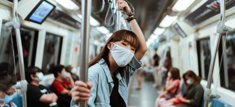 a woman wearing a white face mask on a subway thinking about moving to arlington or mclean