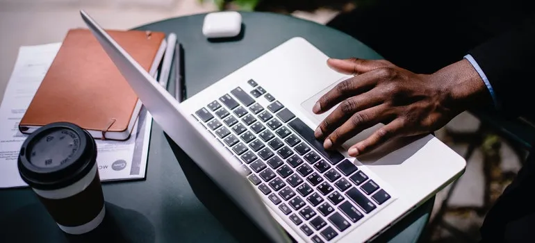 black businessman typing on laptop in street cafe