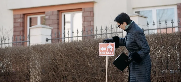 Woman next to the 'for sale' sign
