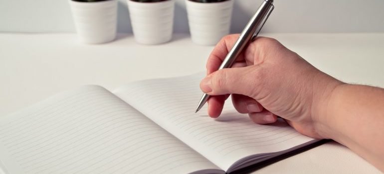 a person writing notes in a notebook about how to relocate your entire household to arlington in a week