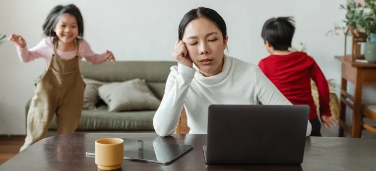 A tired woman looking at her lap top and thinking about why you should never move by yourself