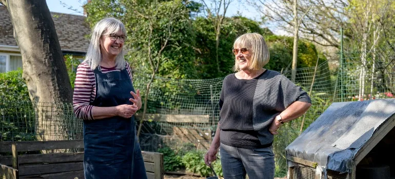 two women chatting in the garden as that is one of the ways to meet your neighbors after moving to Bethesda