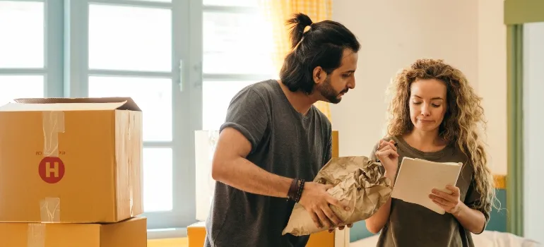 two people writing down something while packing