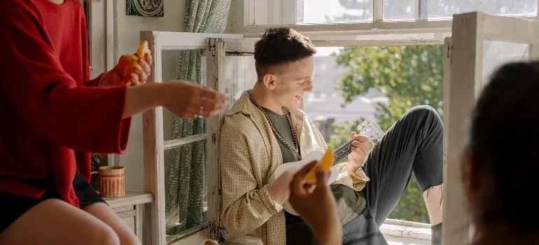 People listening to a man playing his guitar as an example of life during sharing a flat in West Virginia