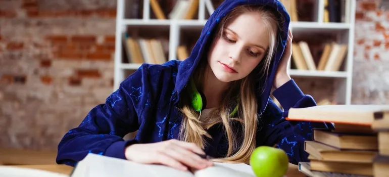 a girl wearing a blue hoodie reading books