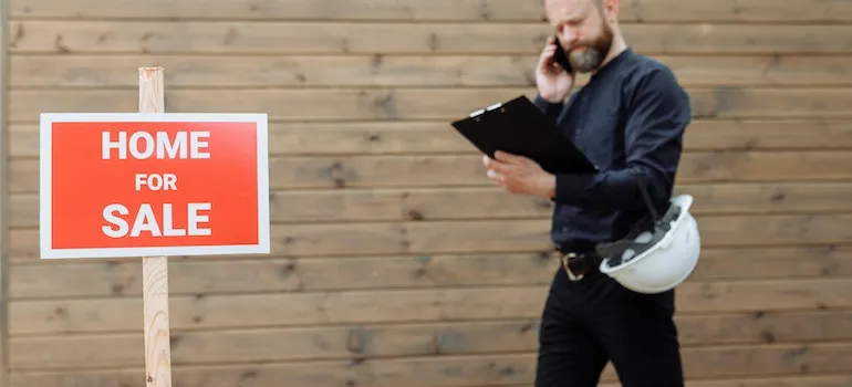 A guy in front of a "Home for Sale" sign considering buying a family house in Northern Virginia