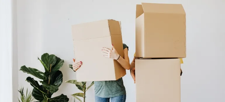 two people holding moving boxes