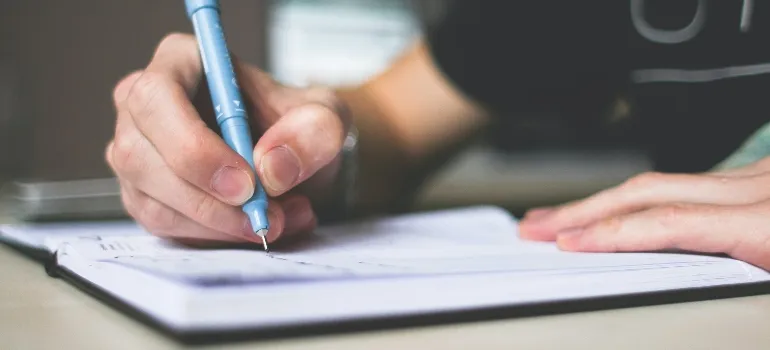 A person writing down an office relocation checklist.