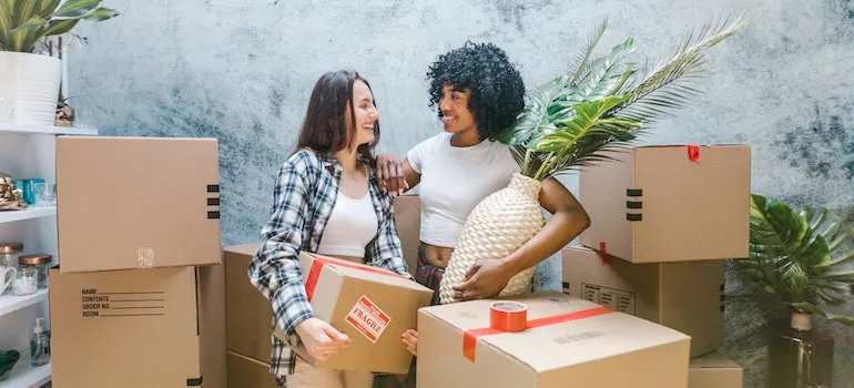 two girl packing their belonging into boxes