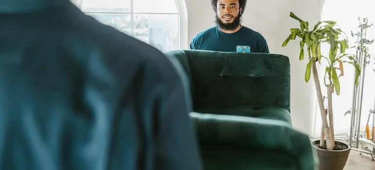 two movers carrying couch as part of full-service moving companies in DMV are