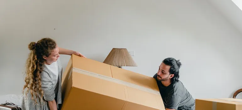 a couple lifting a moving box